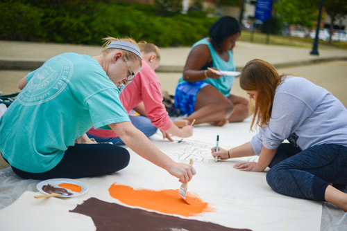 Women on the UTC campus paint a banner