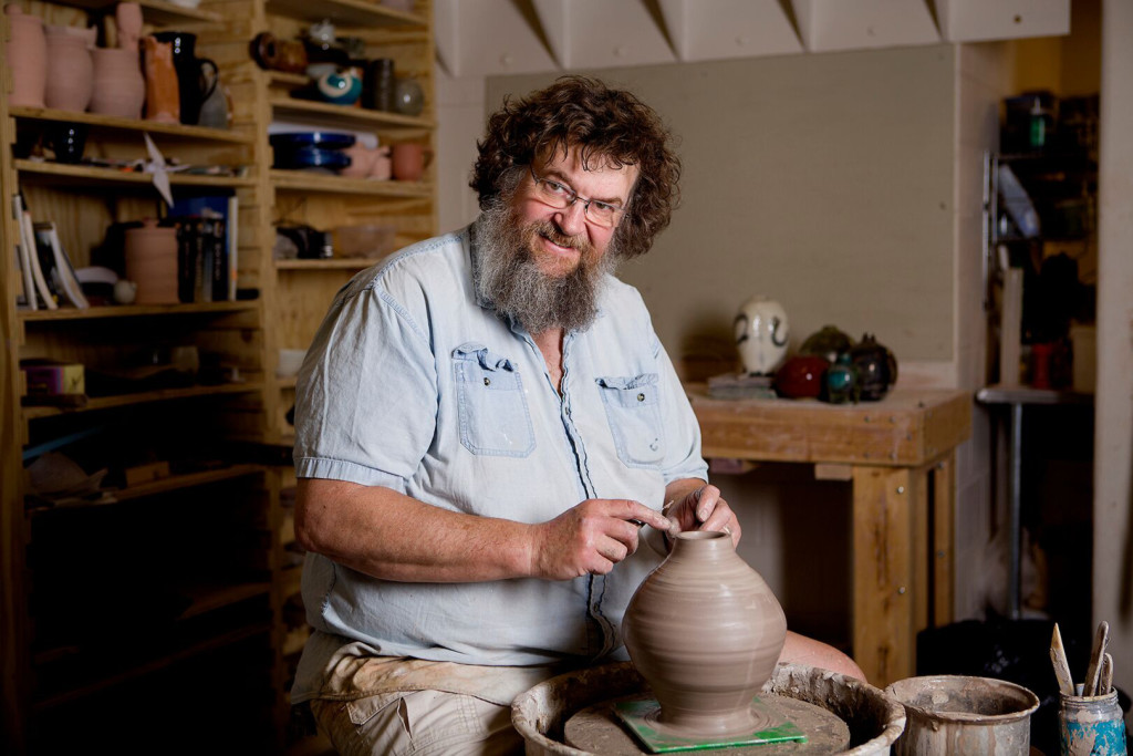 David McBeth pictured in his ceramics studio with a clay jar on a  potter's wheel